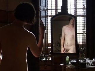A nude Robert Pattinson primps and mimes in front 